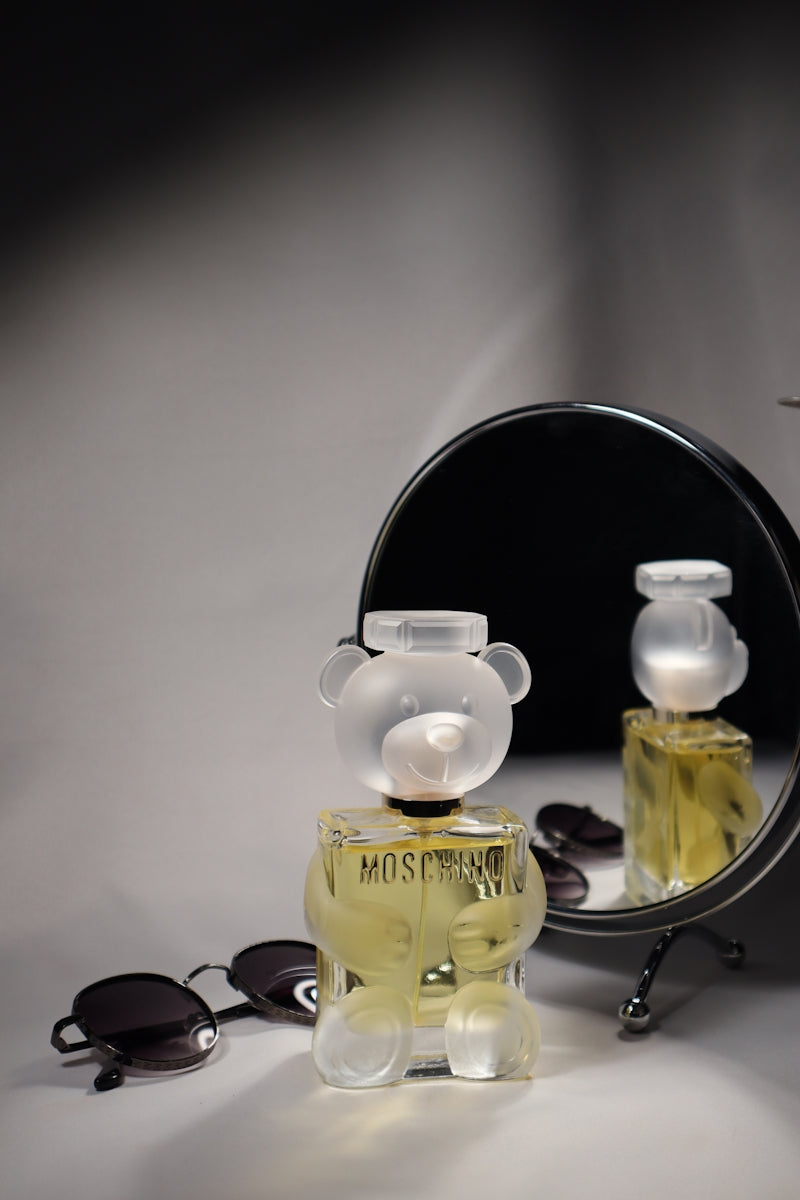 Moschino perfume, glasses, and mirror composition.