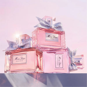 Dior perfume bottles with decorative bows on a light pink background