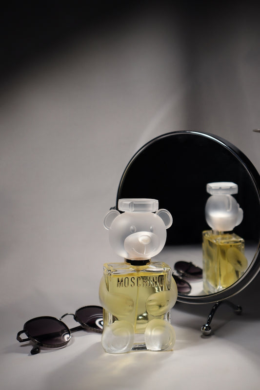Moschino perfume, glasses, and mirror composition.