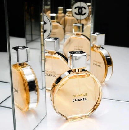 Chanel perfume bottles on a reflective surface with a mirror reflection.
