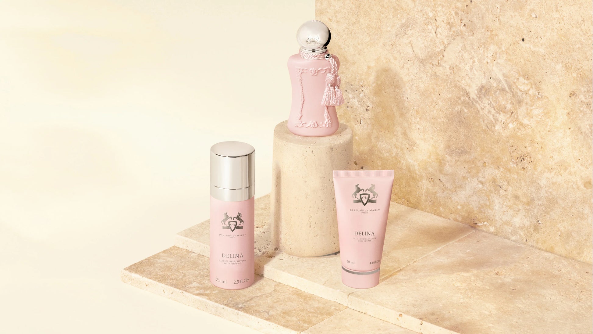 Set of pink Delia  products on a marble surface with a beige stone wall background