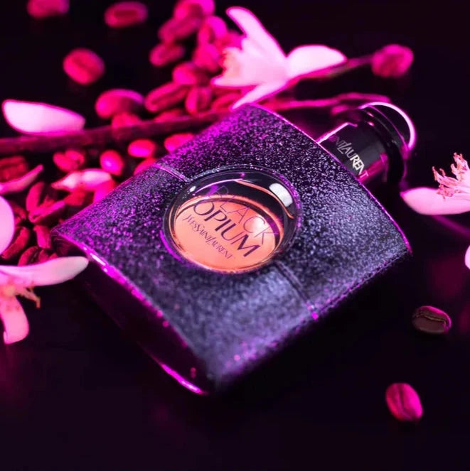 YSL Opium perfume bottle with pink flowers on a dark background
