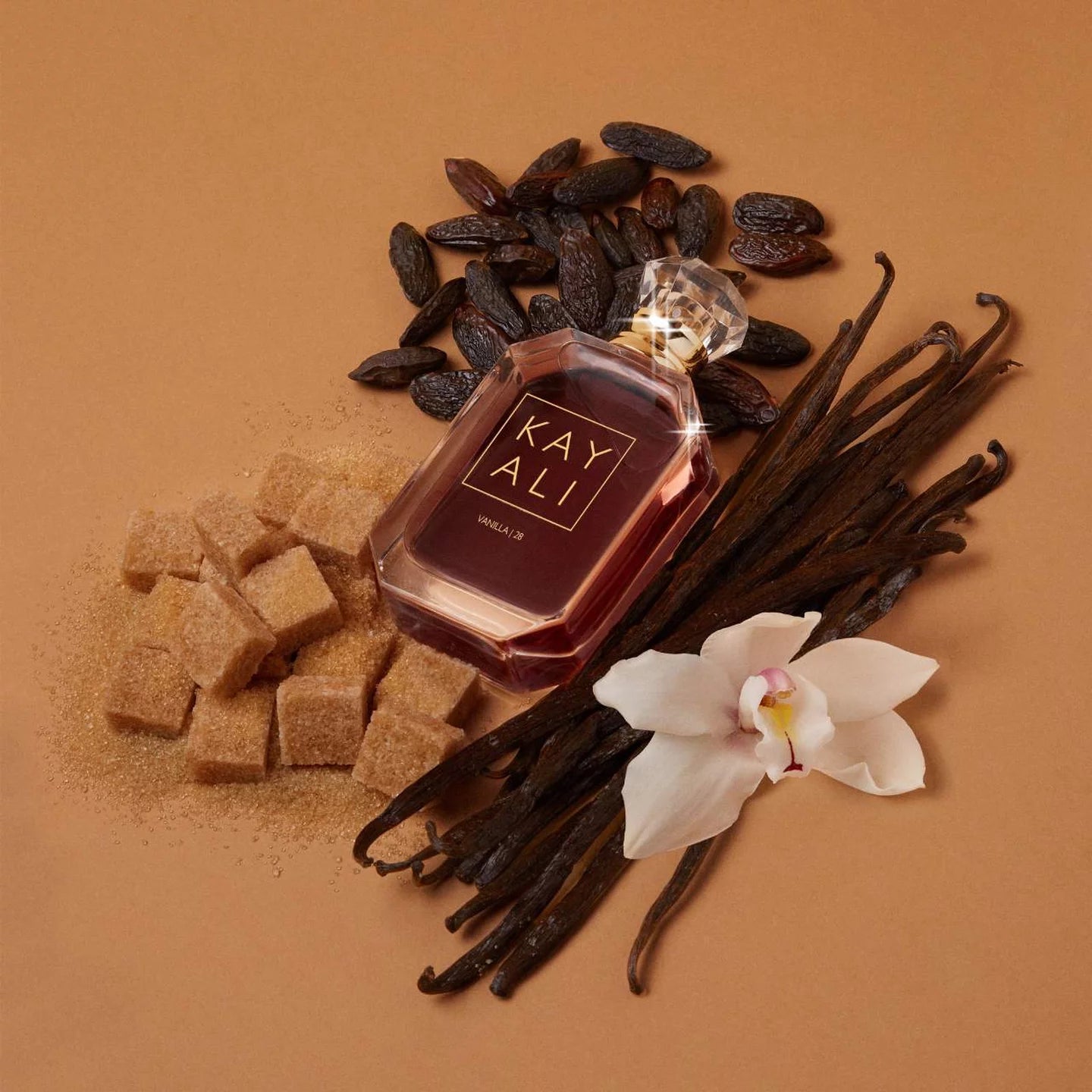 Luxury perfume for women bottle with 'KAY ALI'   surrounded by vanilla beans, sugar cubes, and an orchid on a brown background
