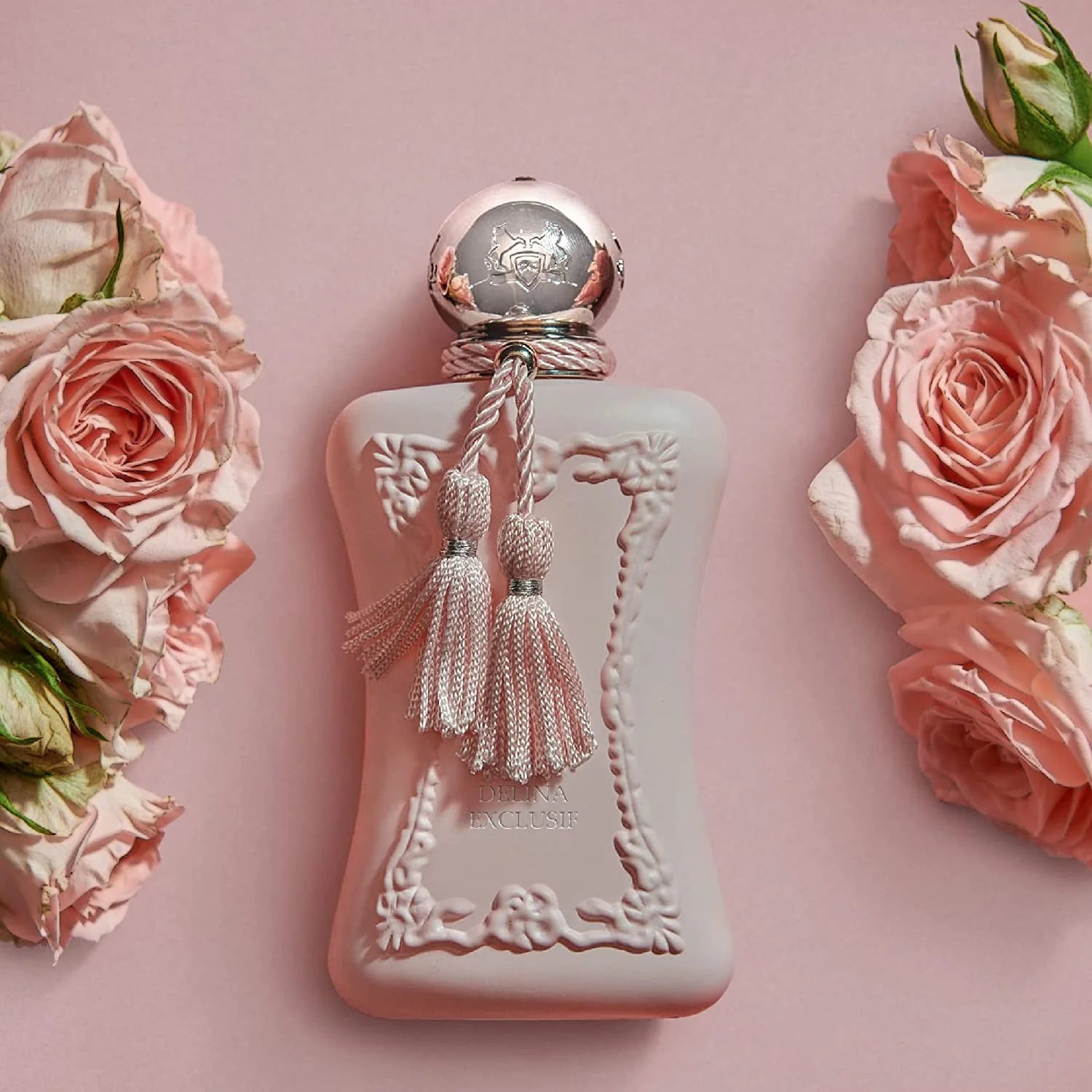delina exclusif Pink perfume bottle with decorative elements on a pink background with pink roses.