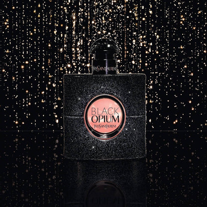Yves Saint Laurent Black Opium perfume bottle on a black background with gold glitter
