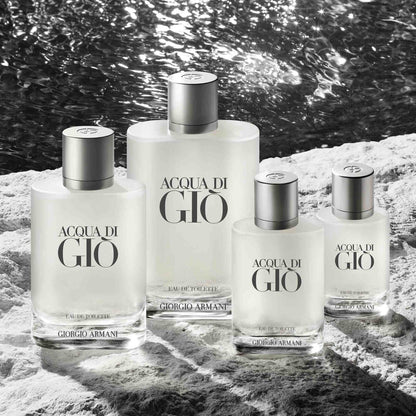 Four bottles of Acqua di Giò by Giorgio Armani on a rocky surface with water in the background.
